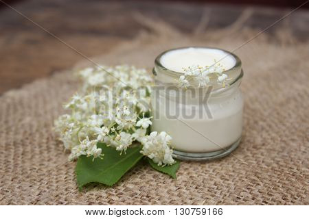 Face cream in a glass jar with chestnut flowers on a background of burlap.Cosmetics.