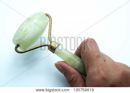 Jade roller acupuncture tool for facial massage with hand.
