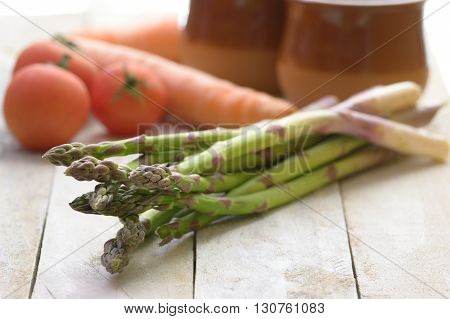Some asparagus on a white wooden table in a rustic kitchen. Empty copy space for Editor's text.