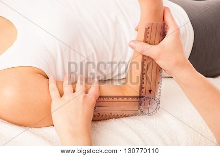 physiotherapy -therapist excercising with patient using gonometer to check the joint mobility of elbow