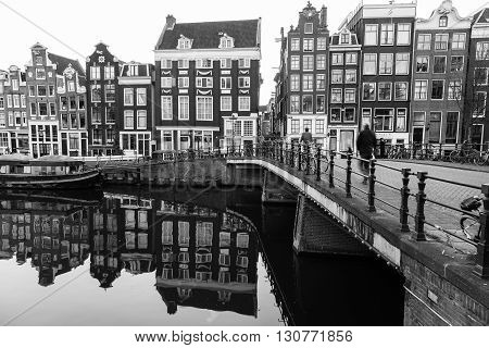 AMSTERDAM NETHERLANDS - 16TH FEBRUARY 2016: A view of buildings and bridges along the Amsterdam Canals. People can be seen.