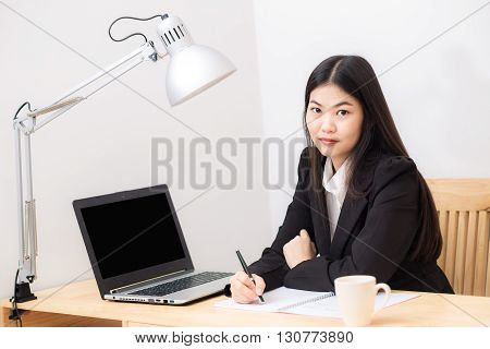 Portrait Of Business Asian Woman With Laptop Writes On A Document