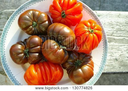 Big Black Heirloom and Oxheart organic tomatoes on wooden textured background