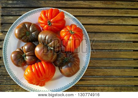 Big Black Heirloom and Oxheart organic tomatoes on wooden textured background