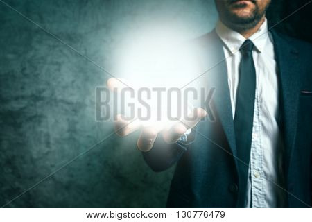 Business vison concept with elegant adult businessman holding bright light of new ideas in hand