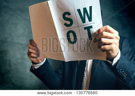 Businessman reading SWOT analysis report documentation male businessperson in office