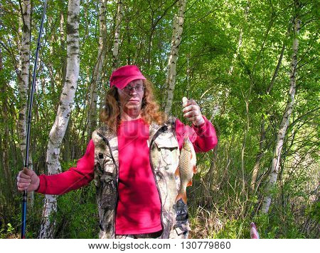 Fisherman with catch, lake in the birch forest