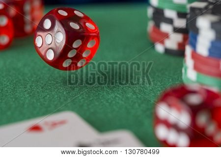 Red casino dice rolls and casino chips on green table