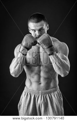The man in boxing gloves. Young Boxer fighter over black background. Boxing man ready to fight. Boxing workout muscle strength power - the concept of strength training and boxing