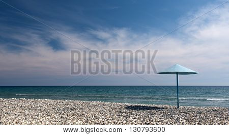 Empty stone peaceful beach with Umbrella on the shore and blue cloudy sky at Larnaca area in Cyprus