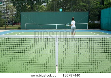 Tennis nets and a woman play with the knock-boards in background.
