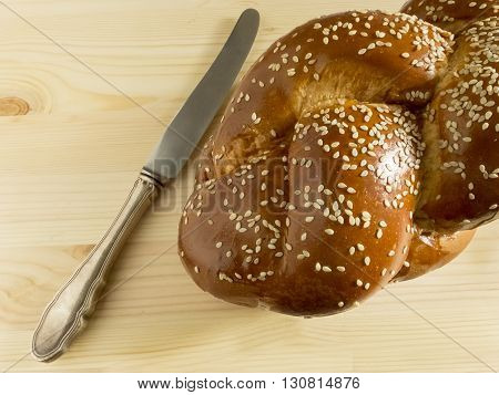 Bright Shabbat challah and knife on wooden background