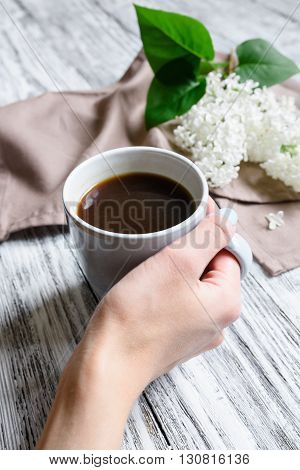 Coffee cup in a female hand on a wooden table