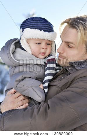 Happy family. Portrait of young father in a winter park with his sweet baby boy