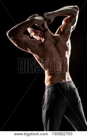 Strong bodybuilder man posing with perfect abs, houlders, biceps, triceps and chest on black background.