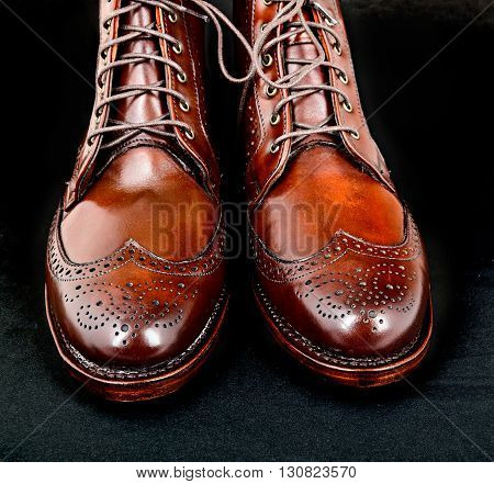 Wingtip dark chili brown dress boots isolated on black background