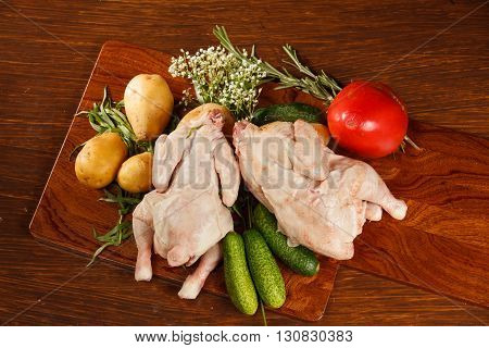 Raw chicken with vegetables on a wooden table