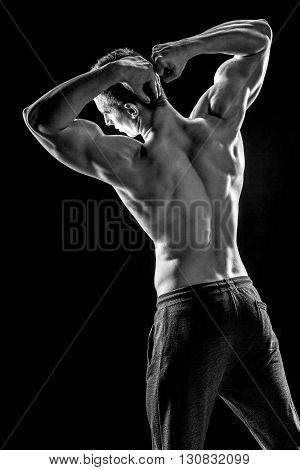 Strong bodybuilder man posing with perfect abs, houlders, biceps, triceps and chest on black background. Black and white