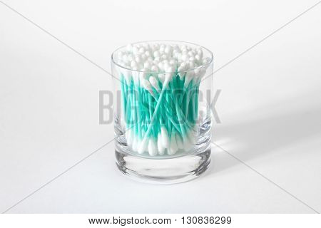 Turquoise cotton swabs in clear glass jar isolated on white