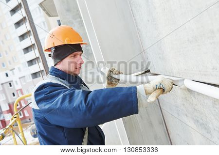 Facade plasterer sealing joint of building wall with putty mastic 