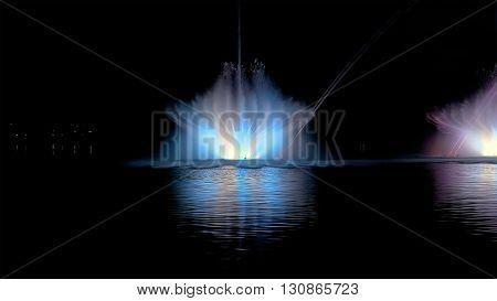 Amazing fantastic colorful fountain with bright illumination on the water pond or river with beautiful reflection at the evening or night. Beauty urban recreational concept.