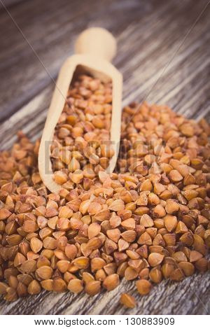Vintage photo Heap of uncooked brown buckwheat groats with spoon on wooden table concept for healthy eating and nutrition