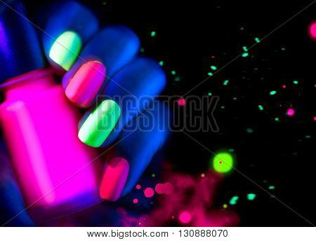 Neon Nails. Fashion model woman nails in neon light, beautiful nail art with fluorescent nail polish, Art design of female colorful disco nailart in UV, Isolated on black background