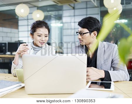 young asian business people sitting at desk working together using laptop computer.