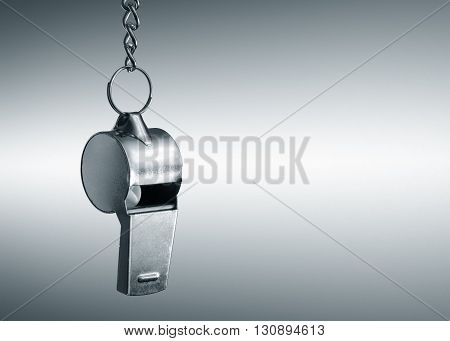 Hanging metal whistle closeup photo. Gray background