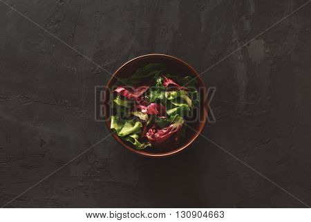 Fresh salad on a dark background top view. Helpful and simple food
