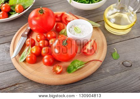 set of tomato on the wooden table with green salad leaves. Ingredients for the preparation of wholesome food