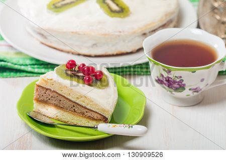 Piece of cake  with cream kiwi and kalina  on white wooden table