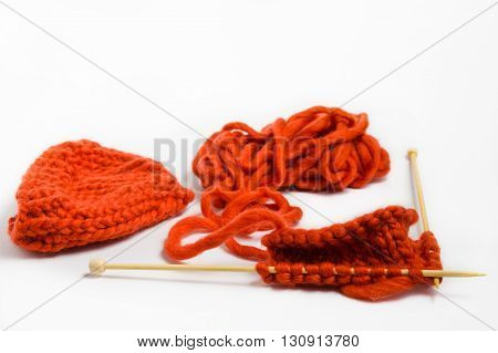 Knitting with wool thick soft orange color yarn on the needles. Yarn and knitting needles isolated on white background.