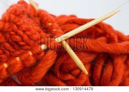 Knitting with wool thick soft orange color yarn on the needles. Yarn and knitting needles isolated on white background.