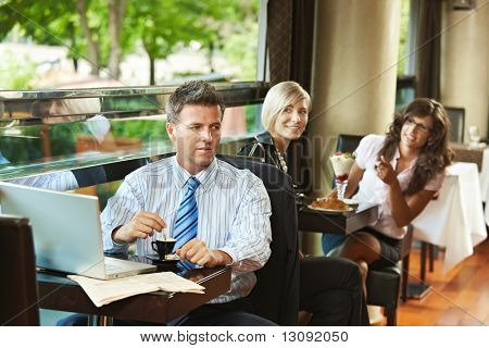 Homme d'affaires à l'aide de portable dans le café, les jeunes femmes à l'arrière-plan l'avait reconnu. Mise au point sélective sur b