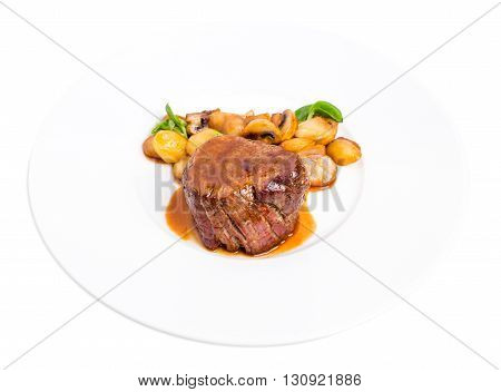 Delicious beef steak in demiglas sauce with vegetable garnish. Isolated on a white background.