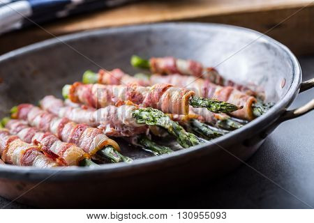Asparagus. Asparagus and roll bacon. Grilled asparagus with rolled bacon and fried egg. Fried old pan full of rolled bacon with green asparagus and fried egg.
