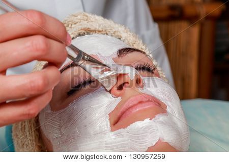 Girl with a beautician at spa salon. Beautician performs cosmetic procedures.applying cosmetic cream. Cosmetology facial beauty - The concept of facial skin care. Article about cosmetology.