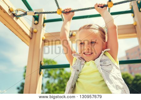 summer, childhood, leisure and people concept - happy little girl on children playground climbing frame