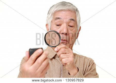 portrait of senior Japanese man with presbyopia on white background