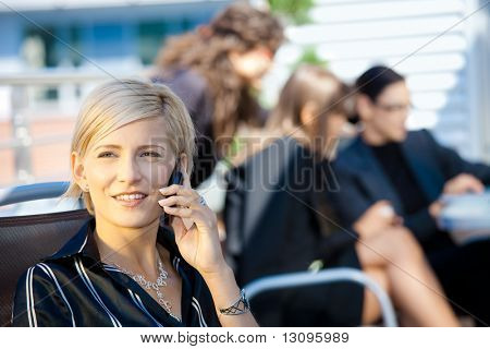Jeune femme d'affaires, parler au téléphone portable, à l'extérieur de l'immeuble de bureaux.