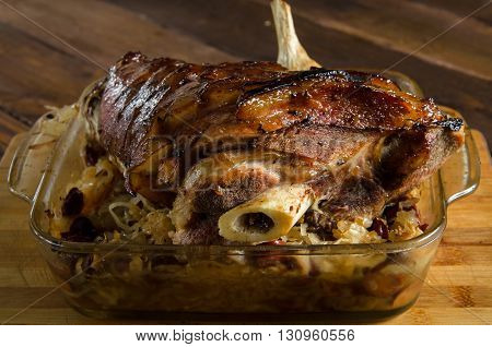 Roasted pork knuckle with braised sauerkraut with sausages on a wooden table