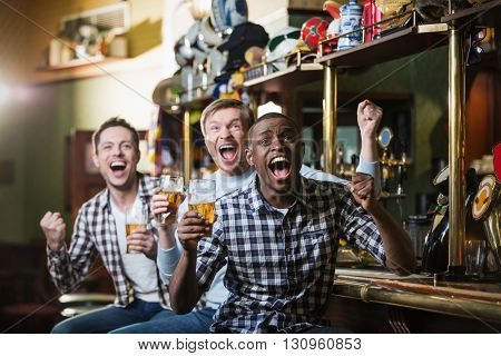 Shouting fans with a beer at a bar