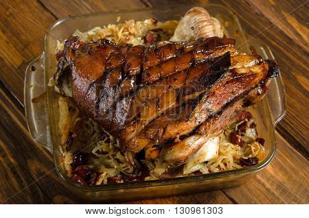 Roasted pork knuckle with braised sauerkraut with sausages on a wooden table