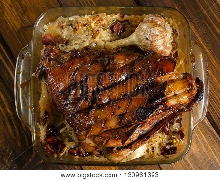 Roasted pork knuckle with braised sauerkraut with sausages on a wooden table