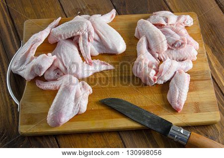 raw chicken wings with knife on wooden table