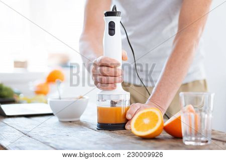 Vitamin For Biohacking. Close Up Of Male Hands Holding Orange Fresh Machine For Drinking Useful Brig