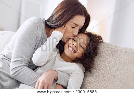 I Love You. Attractive Inspired Loving Dark-haired Woman Smiling And Kissing Her Little Daughter Whi