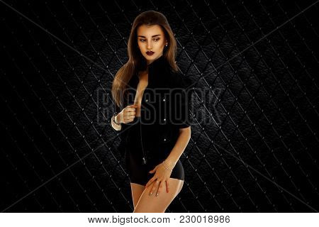 Slender Young Lady In Black Body Stands In The Studio In Front Of A Camera Isolated On White Backgro