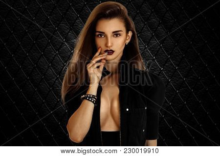 Portrait Of An Attractive Brunette Who Poses In The Studio With Unfastened Black Jacket And Dark Lip